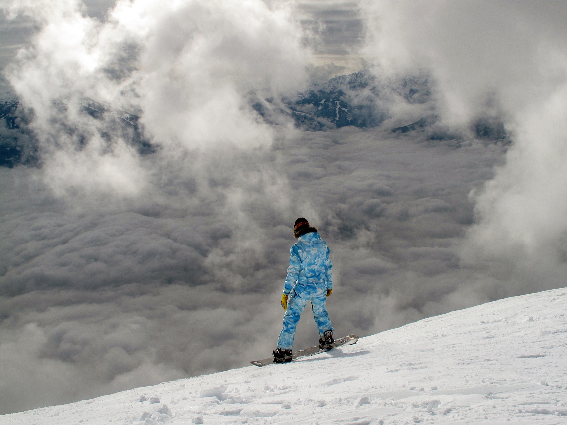 Snowboarder standing at the top of a steep slope